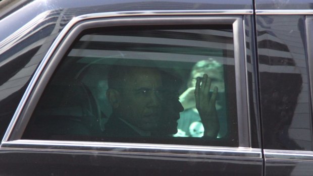 US President Barack Obama waves to people lining the road as he drives through Brisbane.