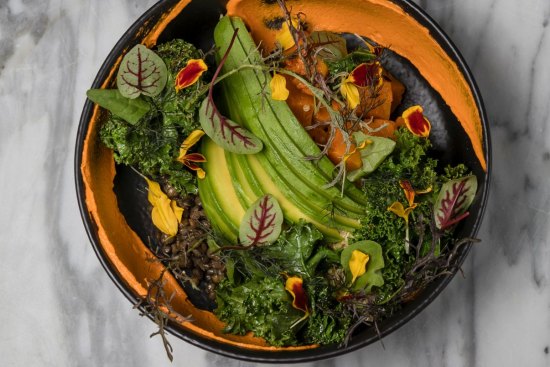 A plant bowl with quinoa, black lentils, pumpkin and preserved lemon tahini.