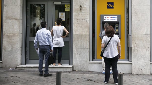 People line up to withdraw cash in Athens on Saturday.