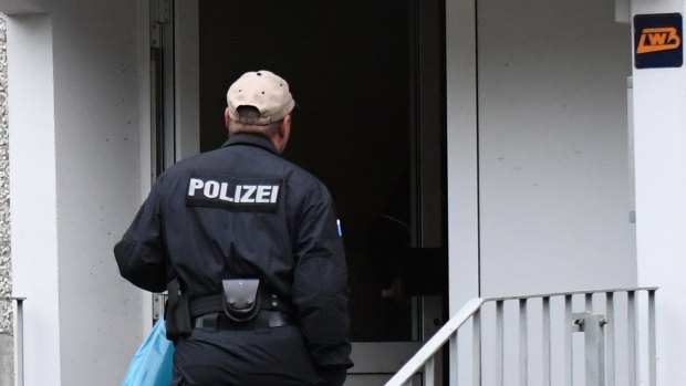 A police officer stands in front of the entrance to an apartment in the Paunsdorf district of Leipzig, Germany.