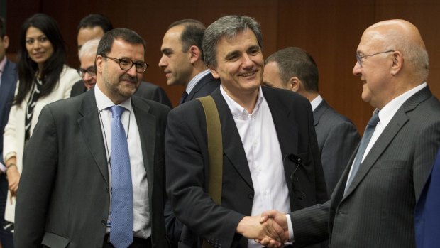 French Finance Minister Michel Sapin (right) shakes hands with his Greek counterpart Euclid Tsakalotos at a Eurogroup meeting in Brussels on Monday.