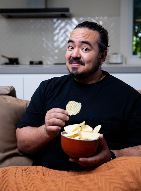 Adam Liaw snacking on salt and vinegar chips at home.