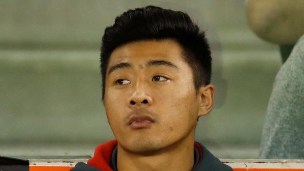 Sidelined: Lin Jong looks on after injuring his knee against the Demons.