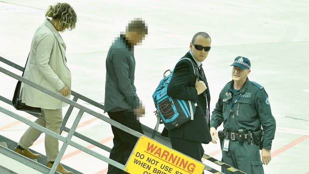 Police take Brodie Wild, left, from a plane which arrived at Melbourne Airport from the Gold Coast on Sunday.