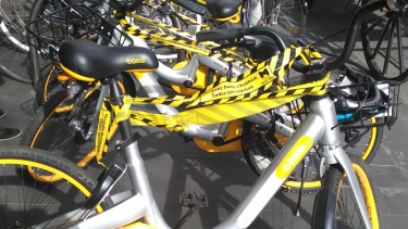 The oBikes appear to be wrapped in official City of Melbourne tape declaring them illegal litter.