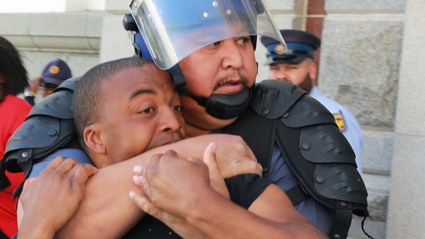 A riot policeman grapples with a student outside the National Assembly in Cape Town.