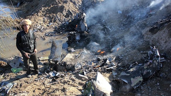 An Islamic State fighter collects pieces from the remains of a Jordanian warplane in Syria's Raqqa region.