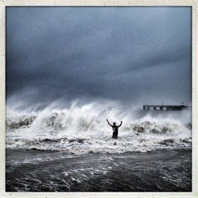 A man stands in the heavy surf near Coney Island as superstorm Sandy makes landfall on October 29, 2012, in New York.