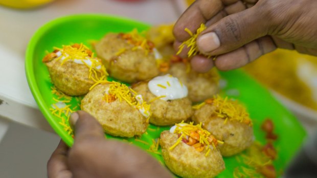 A Mumbai street-food hawker garnishes pani puri - fried pastry shells stuffed with chutney, potato, herbs and spices.