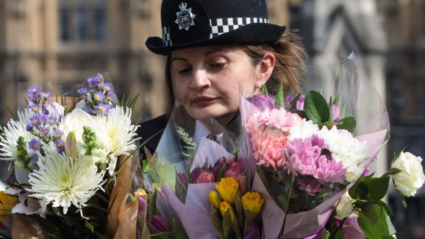 A police officer with floral tributes for the dead.