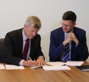 Genex executive director Simon Kidston and Energy Minister Mark Bailey sign the Palaszczuk government's first Solar 150 formal deed of agreement.