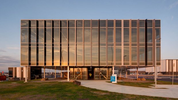 Mirrat's new office at Web Dock designed by Plus Architecture. The simple tinted glass Miesian box elevated on pilotis is Australia's first 6-star green star facility of its kind.