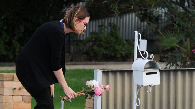 A well-wisher leaves flowers outside the home where Ora Holt and Greg Floyd died.