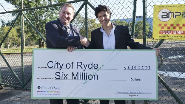 Ryde mayor Bill Pickering receives a cheque for the Macquarie Park site from Liberal MP Victor Dominello during the election campaign.
