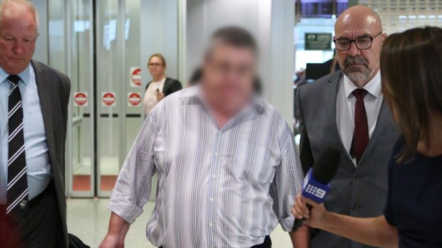 Detectives escort a 63-year-old man through Sydney Airport before he is charged with murder.