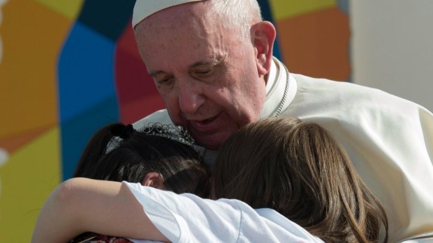 Pope Francis hugs two girls he invited on stage during a meeting with Mexican youth at the Jose Maria Morelos y Pavon Stadium in Morelia, Mexico.