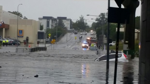 A small hatchback is swept away by flooding in suburban Brisbane.