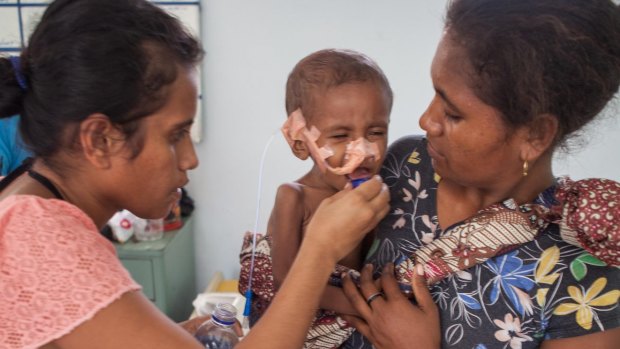 A malnourished child with mother and a nurse in Dili.