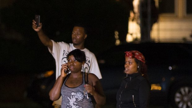 Bystanders watch as a crowd gathers following the fatal shooting of a man in Milwaukee.