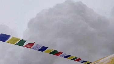 A huge cloud of snow cascades down the mountain.
