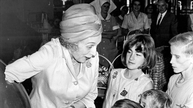 Lady Lloyd Jones plunges her arm deep into a giant Easter egg to get pieces for children at the Royal Alexandra Hospital for Children, Camperdown, in 1966.