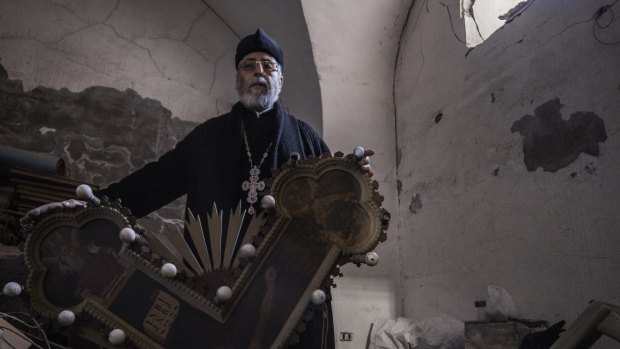Father Andreus Tamer displays smashed crosses and icons.