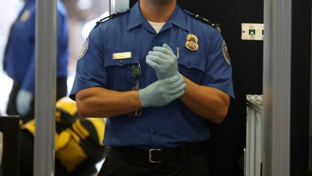 A Transportation Security Administration agent waits for passengers to pass through a magnetometer at Los Angeles International Airport.