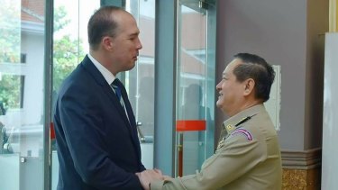 Australian Immigration Minister Peter Dutton and Cambodian Department of Immigration director-general Sok Phal shake hands in Phnom Penh last month.