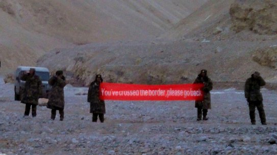 Chinese troops hold a banner reading "You've crossed the border, please go back" in Ladakh, India. 