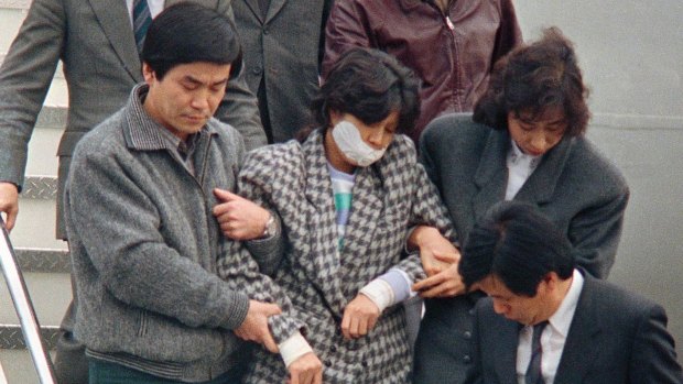 In this 1987 photo, Kim Hyon-hui, with her mouth taped, is taken out from a plane upon her arrival in Seoul,