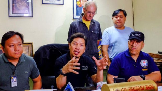 Alleged Australian sex offender Peter Gerard Scully stands behind Philippines police investigator Angelito Magno.