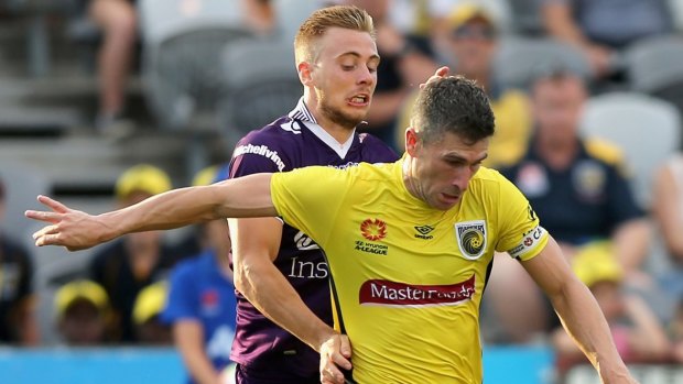Nick Montgomery of the Mariners is tackled by Joseph Mills of Perth Glory.