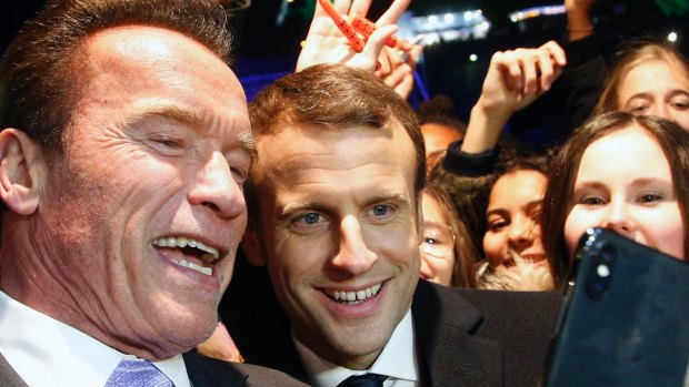 French President Emmanuel Macron, centre, and former California governor Arnold Schwarzenegger take a selfie in Paris on Tuesday.