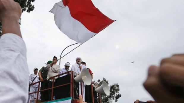 Muslim protesters raise their fists as the leader of Islamic Defenders Front, Rizieq Shihab, gives a speech during a protest against Ahok in October.