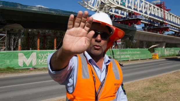 A security guard attempts to stop photographs of the buckled span on the Skytrain viaduct in Sydney's north-west.