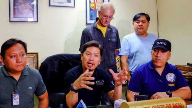 Alleged Australian sex offender Peter Gerard Scully stands behind Philippines police investigator Angelito Magno