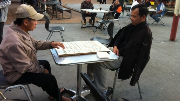 Men playing checkers at Inala Plaza.