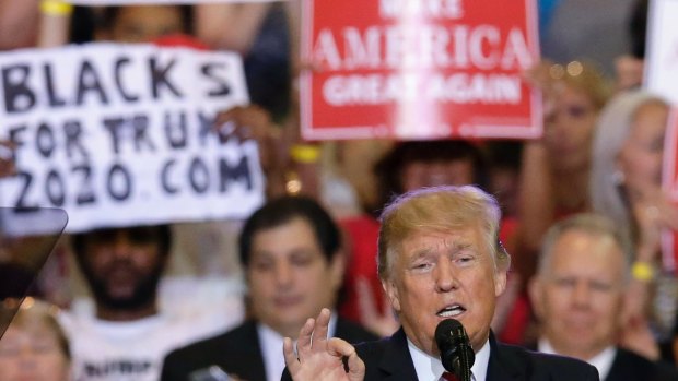 President Donald Trump speaks at a rally at the Phoenix Convention Centre.- a 'Blacks for Truth' sign in the background.
