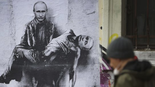 People pass by artwork representing Russia's President Vladimir Putin carrying his own dead body created by the Bulgarian artist Stanislav Belovski, applied on a wall in central Sofia, on day 36 of the Russian invasion in Ukraine, Thursday, March 31, 2022. (AP Photo/Valentina Petrova)