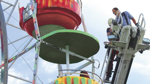 A fire chief stands on the top of a ladder at the Ferris wheel after the accident. 