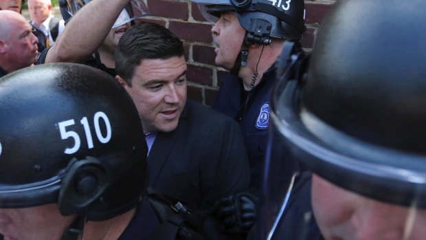 Unite the Right rally organiser Jason Kessler is escorted by police after his press conference was disrupted by protestors on Sunday.