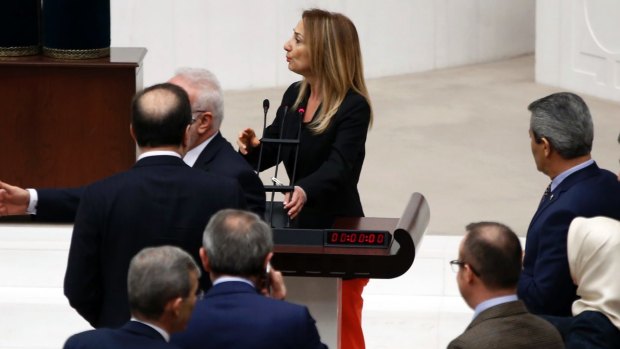 Independent Aylin Nazliaka, rear, handcuffed herself to the parliament's rostrum in protest at the contentious reform package.