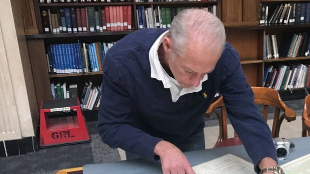 Amateur wartime historian Charles Tennyson studies a map of the Nelson Bay military site at the State Library of NSW.