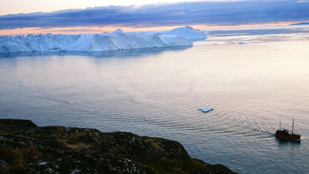 A boat sails by an iceberg in the Jacobshavn Bay, August 28, 2007 near the town of Ilulissat, Greenland. 