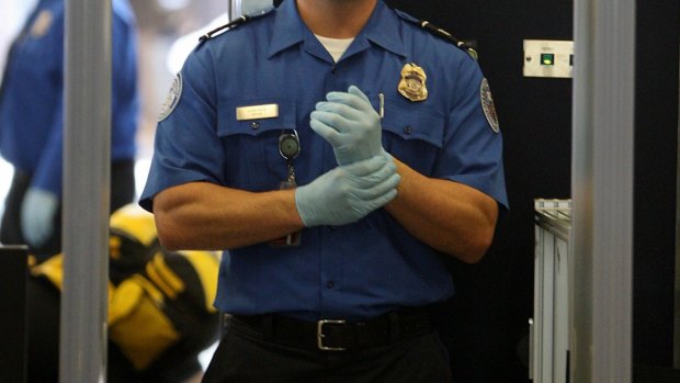 A TSA agent waits for passengers to pass through a magnetometer at Los Angeles International Airport.