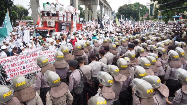Supporters of the FPI face off with some of  the 2800 police who were brought in outside Indonesian police HQ in Jakarta.