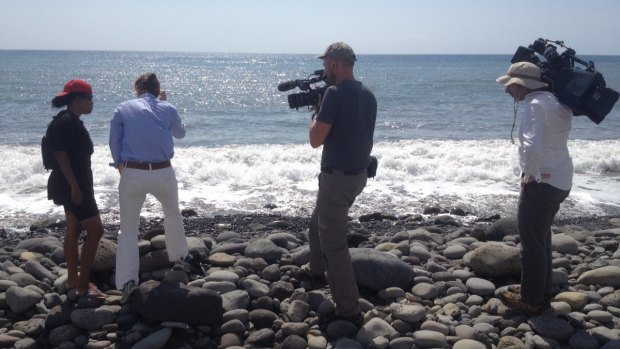 Reporters shown the spot where a small piece of metal was found on a beach in Saint-Denis, Reunion Island. Police have take the object away.