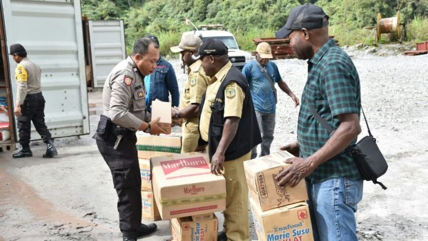 Police hand over food and supplies to local villagers from inside a mining area where there is conflict between the West Papua National Liberation Army and security forces. 