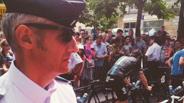 A police officer watches on as Team Sky riders prepare for the day.