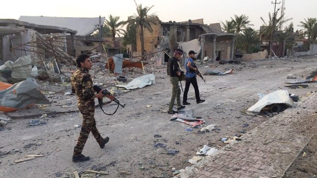 Iraqi security forces and tribal fighters walk down a street after regaining control of the northern neighborhoods of Ramadi.